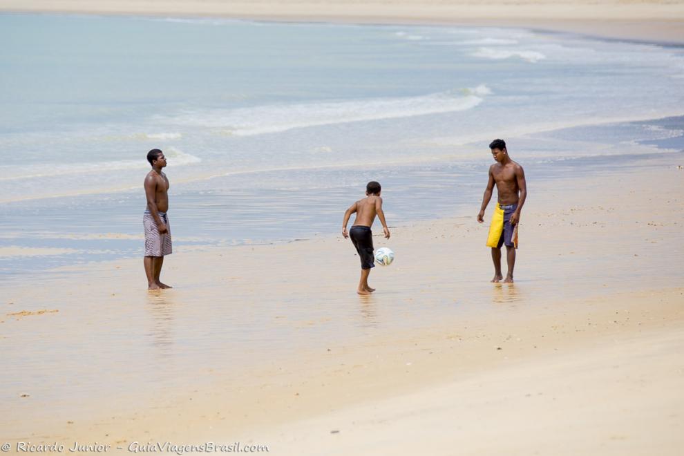Imagem de meninos jogando bola na beira do mar na Praia de Corumbau.